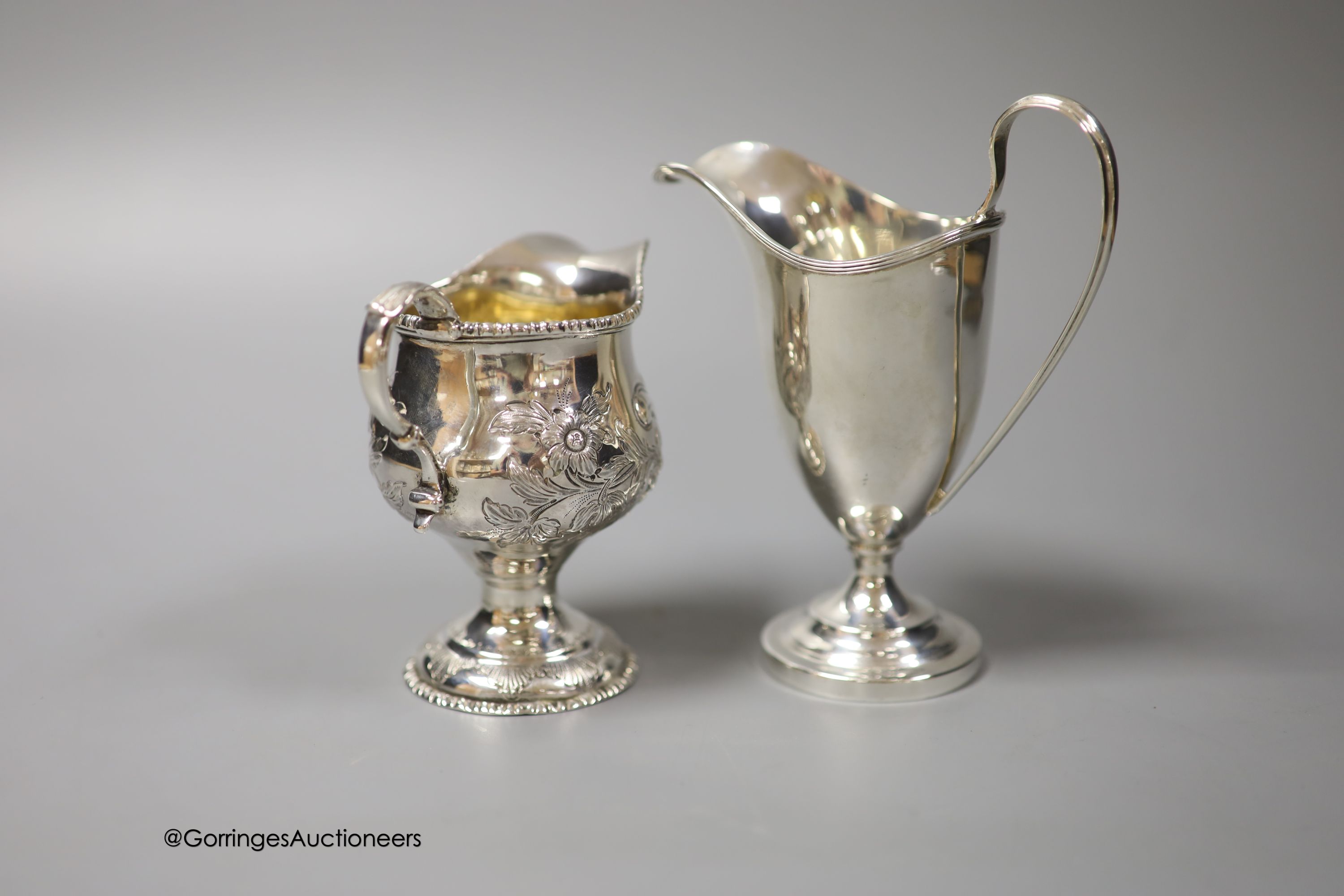 A George III silver inverted pear shaped cream jug, with later embossed decoration, marks rubbed, 9.7cm and a later cream jug, gross 210 grams.